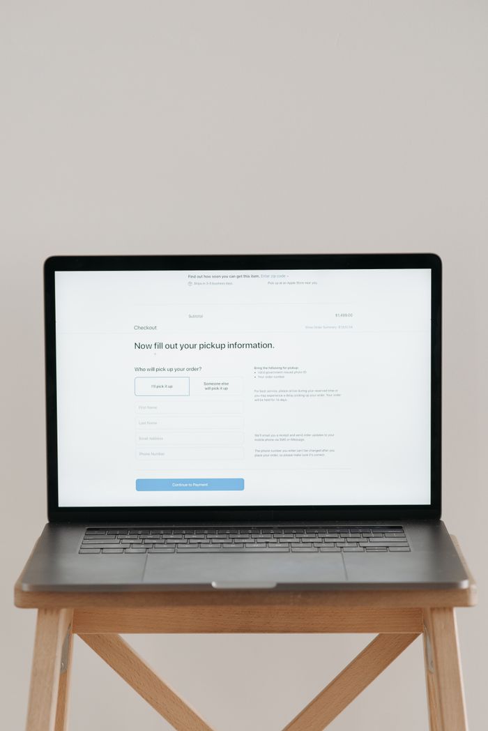 Modern laptop displaying a checkout form against a minimalist beige backdrop.